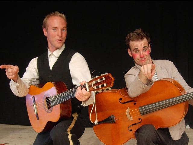 Mann mit Clownnase mit Bass und zweiter Mann mit Gitarre in der Hand auf Bühne. Mann mit Clownnase mit Bass und zweiter Mann mit Gitarre in der Hand auf Bühne.