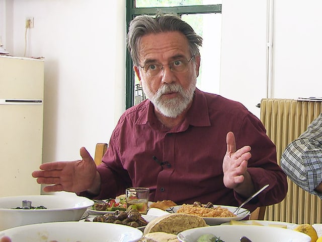Mann mit Bart an einem Tisch mit Tellern und Esswaren. Mann mit Bart an einem Tisch mit Tellern und Esswaren.