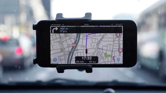 Ein Handy klebt an einer Windschutzscheibe, installiert die Verkehrs-App Waze. Ein Handy klebt an einer Windschutzscheibe, installiert die Verkehrs-App Waze.