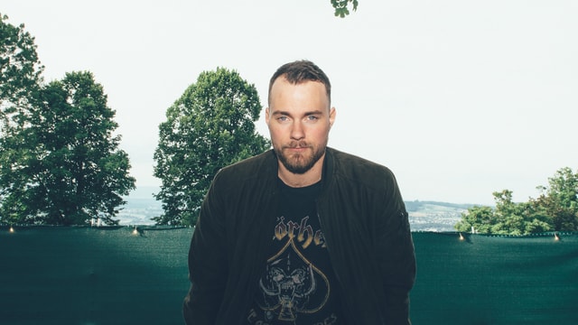 Ásgeir lehnt sich an eine Bank und lächelt in die Kamera Ásgeir lehnt sich an eine Bank und lächelt in die Kamera