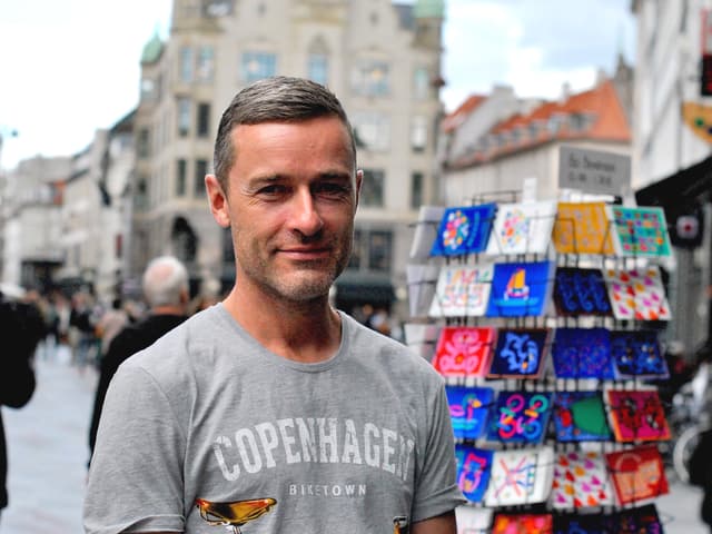 Der Kopenhagener Souvenirverkäufer Jacob Lentz vor einem Postkartenständer
