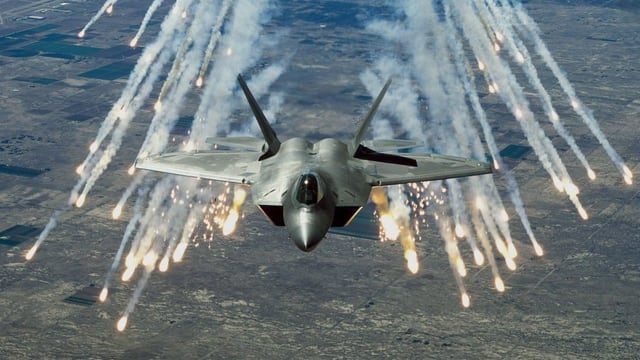 Ein Kampfjet feuert hell aufblitzende Flugkörper ab Ein Kampfjet feuert hell aufblitzende Flugkörper ab