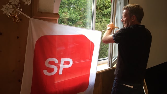 Ein Mann hängt eine SP-Transparent an ein Fenster. Ein Mann hängt eine SP-Transparent an ein Fenster.
