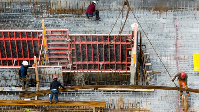 Blick auf eine Baustelle von oben, auf der Arbeiter Armierungseisen legen. Blick auf eine Baustelle von oben, auf der Arbeiter Armierungseisen legen.