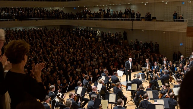 Voller Konzertsaal, auf der Bühne ein Orchester Voller Konzertsaal, auf der Bühne ein Orchester