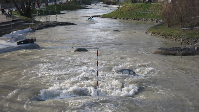 Ein breiter Bach mit Stromschnellen, im Hintergrund paddelt einer. Ein breiter Bach mit Stromschnellen, im Hintergrund paddelt einer.