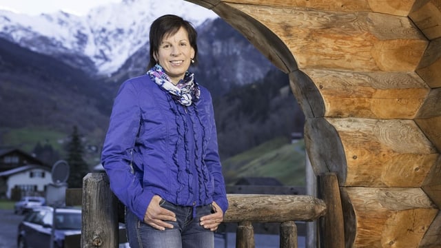Frau in blauer Jacke vor Stalltor und Bergpanorama. Frau in blauer Jacke vor Stalltor und Bergpanorama.