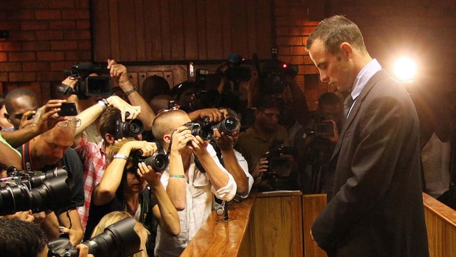 Oscar Pistorius mit gesenktem Kopf, vor ihm Dutzende Journalisten Oscar Pistorius mit gesenktem Kopf, vor ihm Dutzende Journalisten