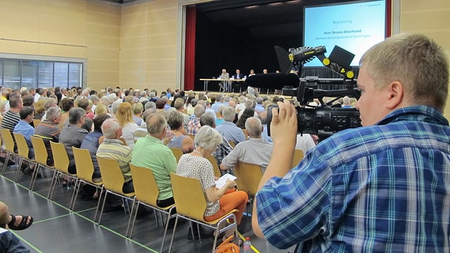 Kameramann filmt in einem Saal, wo es viele Leute hat. Kameramann filmt in einem Saal, wo es viele Leute hat.