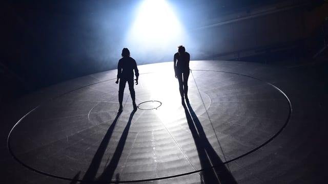 Zwei Menschen auf einer Bühne. Sie werde mit Licht bestrahlt. Zwei Menschen auf einer Bühne. Sie werde mit Licht bestrahlt.