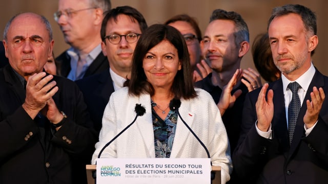 Hidalgo at the lectern, surrounded by cheering men.