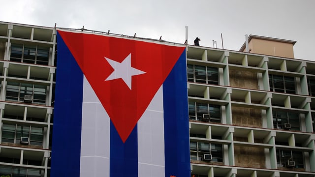 Riesige Kuba-Flagge hängt vom Flachdach des Innenministeriums in Havanna herunter Riesige Kuba-Flagge hängt vom Flachdach des Innenministeriums in Havanna herunter