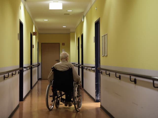 Ein alter Mann im Rollstuhl in einem Gang Ein alter Mann im Rollstuhl in einem Gang