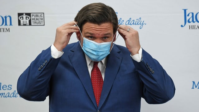 Ron DeSantis legt sich eine Hygienemaske an. Ron DeSantis legt sich eine Hygienemaske an.