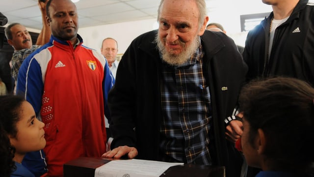 Fidel Castro gibt seine Stimme ab. Im Vordergrund zwei kleine Kinder. Links von Castro ein Mann im Trainingsanzug. Fidel Castro gibt seine Stimme ab. Im Vordergrund zwei kleine Kinder. Links von Castro ein Mann im Trainingsanzug.