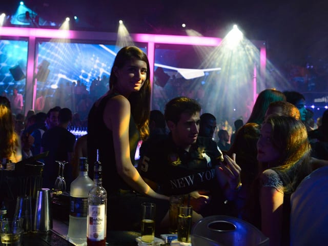 Eine junge Frau steht in einem Nachtclub an einer Bar. Eine junge Frau steht in einem Nachtclub an einer Bar.