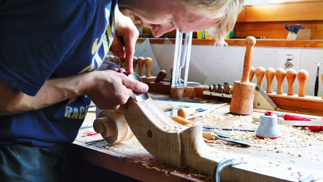 Ein junger Mann hobelt an einer Werkbank. Ein junger Mann hobelt an einer Werkbank.