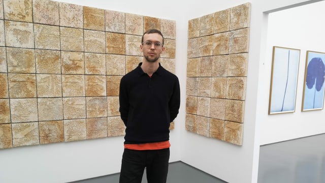 Mann in schwarzer Kleidung vor beigen Platten an der Wand. Mann in schwarzer Kleidung vor beigen Platten an der Wand.