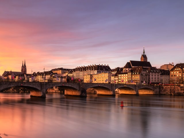 Stadt mit Brücke über Fluss. Der Himmel in gelb bis rot