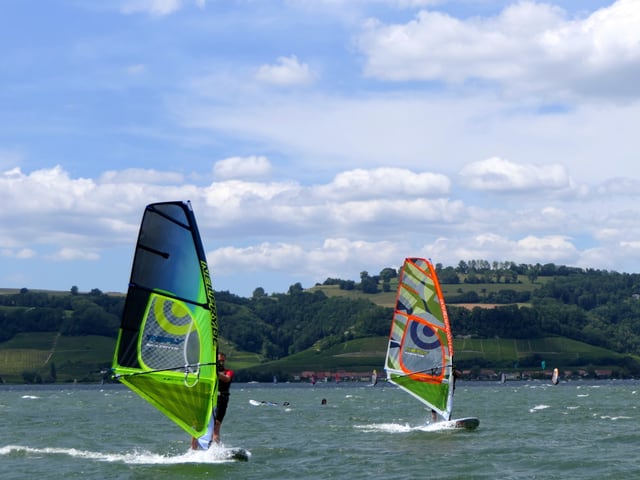 Zwei Surfer geniessen den kräftigen Wind auf dem See.