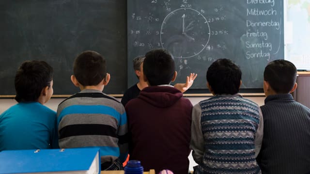 Junge Flüchtlinge in einem Schulzimmer vor einer Wandtafel. Junge Flüchtlinge in einem Schulzimmer vor einer Wandtafel.