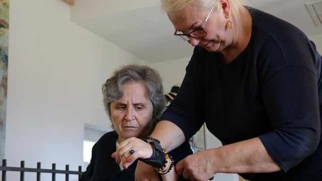 Die Pflegefachkraft hilft der alten Frau den Pullover anzuziehen. Die Pflegefachkraft hilft der alten Frau den Pullover anzuziehen.