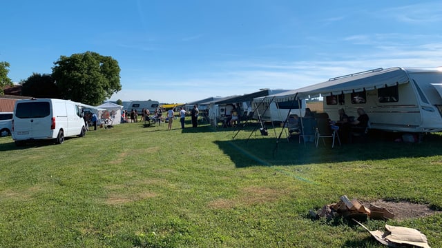 Wiese mit Wohnwagen, vorne rechts eine Feuerstelle Wiese mit Wohnwagen, vorne rechts eine Feuerstelle
