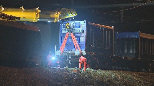 Kran hebt Zugwagen hinter der entgleisten Lokomotive an. Kran hebt Zugwagen hinter der entgleisten Lokomotive an.