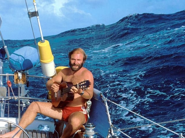 Mann sitzt auf Segelschiff im Hintergrund wirft das Meer hohe Wellen. Mann sitzt auf Segelschiff im Hintergrund wirft das Meer hohe Wellen.
