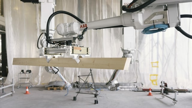 Ein Roboterarm greift ein Holzbauelement.