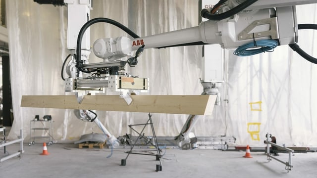 Ein Roboterarm greift ein Holzbauelement. Ein Roboterarm greift ein Holzbauelement.