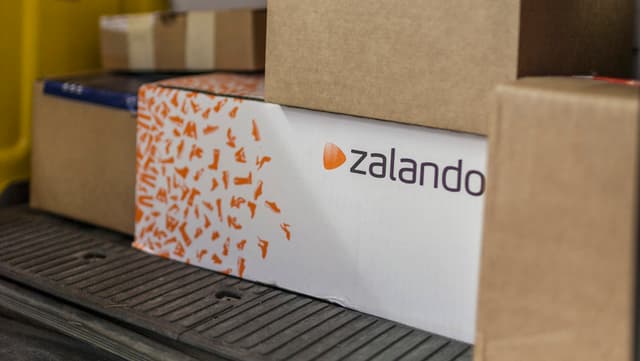 Ein Paket von Zalando in mitten anderer Pakete in einem Lieferwagen der Post.