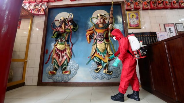 Mann desinfiziert den Nana Dasana Temple in Jakarta. Mann desinfiziert den Nana Dasana Temple in Jakarta.