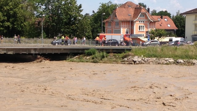 Nach der Flutwelle im Oberlauf (Schangnau) erreicht das Emme Hochwasser Biberist. Das schlamige Wasser strömt gerade noch unter einer Brücke hindurch.