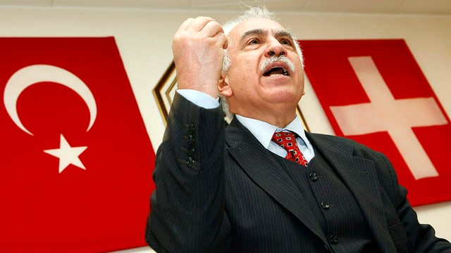 Dogu Perincek, Fahnen (türkische und schweizerische) an der Wand Dogu Perincek, Fahnen (türkische und schweizerische) an der Wand