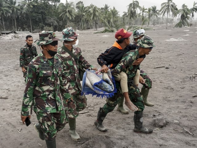 Personel TNI mengevakuasi seorang warga dari kawasan yang terkena erupsi Gunung Semeru.