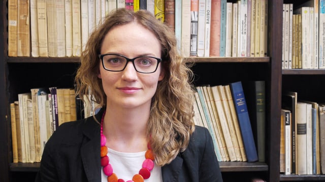 Eine junge Frau steht vor einem Bücherregal. Eine junge Frau steht vor einem Bücherregal.