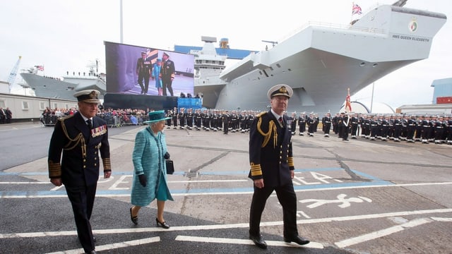 Queen geht an Schiff vorbei, dahinter Soldaten. Queen geht an Schiff vorbei, dahinter Soldaten.