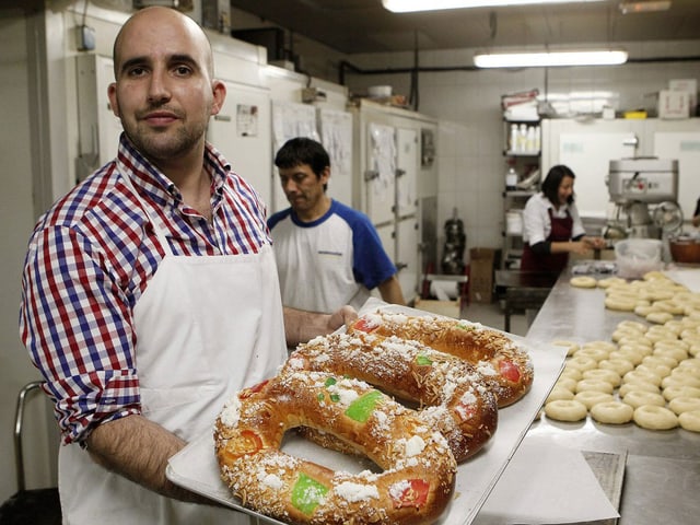 Mann hält zwei spanische Königskuchen auf einem blech in der Hand. Mann hält zwei spanische Königskuchen auf einem blech in der Hand.