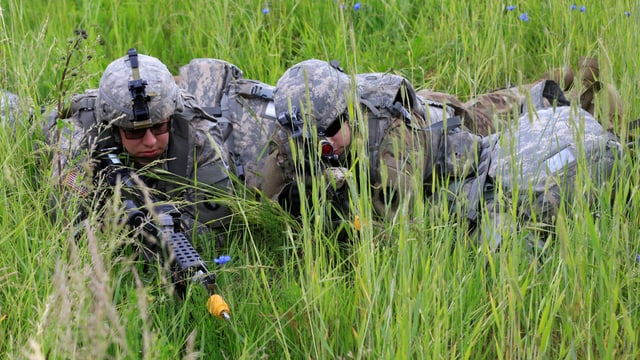 Bewaffnete Soldaten liegen im hohen Gras. Bewaffnete Soldaten liegen im hohen Gras.