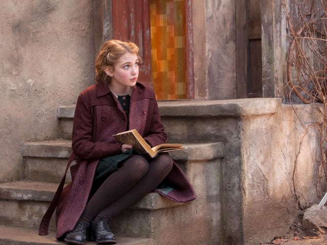 Mädchen sitzt auf Treppenstufen mit einem Buch auf den Knien. Mädchen sitzt auf Treppenstufen mit einem Buch auf den Knien.