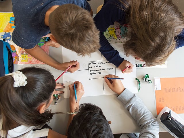 Vier Kinder schreiben auf ein Papier Vier Kinder schreiben auf ein Papier