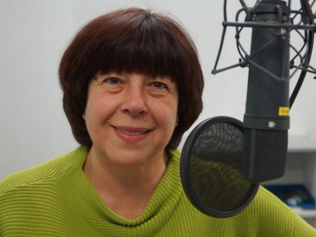 Frau mit grünem Pullover hinter Mikrofon. Frau mit grünem Pullover hinter Mikrofon.