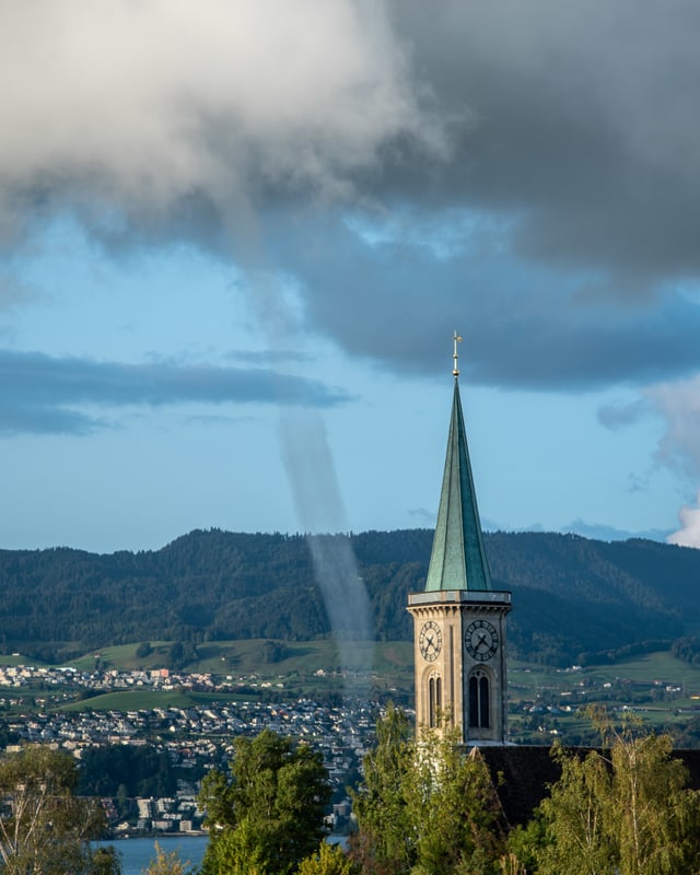 Wasserhose über dem See neben einem Kirchturm.