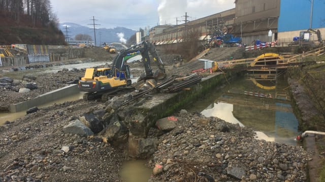 Ein grosser Bagger schaufelt im Flussbett der Kleinen Emme Geröll weg. Ein grosser Bagger schaufelt im Flussbett der Kleinen Emme Geröll weg.