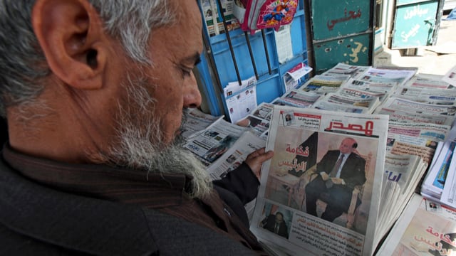 Ein Mann hält eine Zeitung in der Hand. Ein Mann hält eine Zeitung in der Hand.