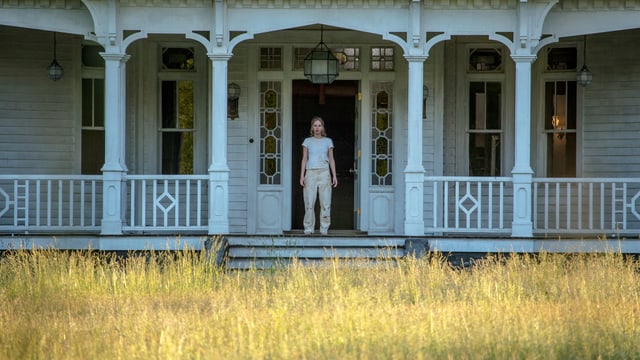 Veranda eines Hauses, dort steht eine Frau Veranda eines Hauses, dort steht eine Frau