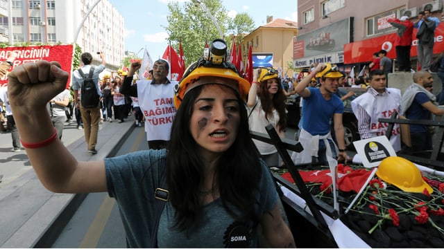 Eine Demonstrantin mit Bauarbeiterhelm reckt die Faust in die Höhe. Eine Demonstrantin mit Bauarbeiterhelm reckt die Faust in die Höhe.