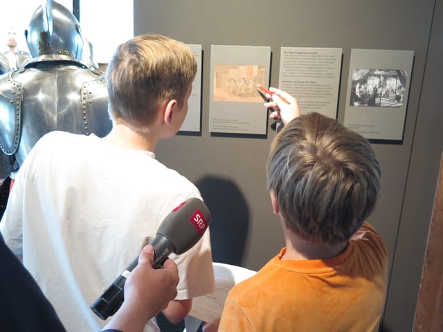 Zwei Buben diskutieren vor einer Tafel im Museum. Zwei Buben diskutieren vor einer Tafel im Museum.