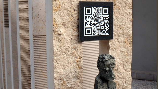 Ein Schild mit einem QR-Code auf einem Grabstein. Ein Schild mit einem QR-Code auf einem Grabstein.